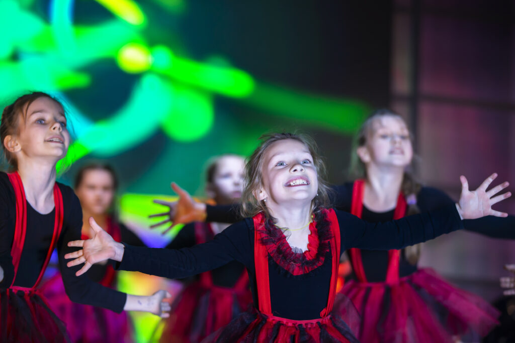 Little girls are performing a dance number. Dance for Helovinna in red suits. Girl dancing. Emotional performance of a children's dance group.