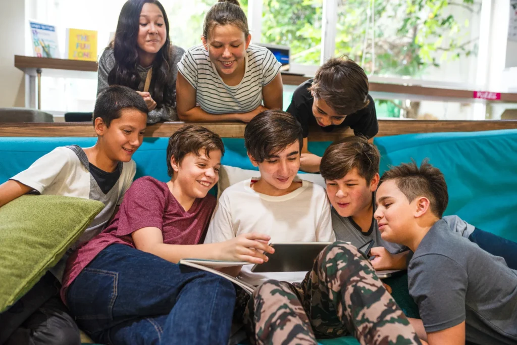 group diverse kids boys girls gathered around laptop smiling engaged kids enjoying technology learning fun together couch school kids learning together with technology